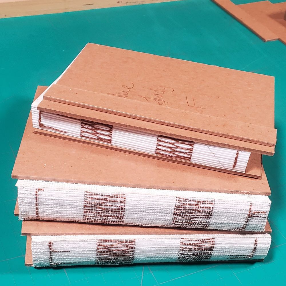 Stack of three text blocks and binder board covers on cutting mat