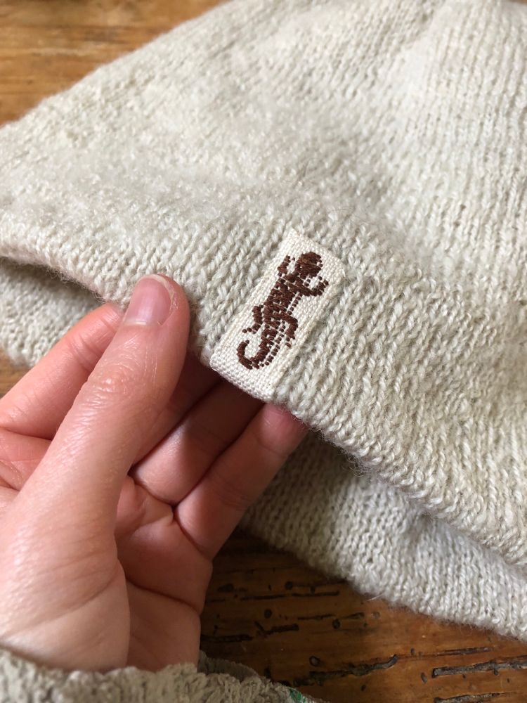Close up of a woven garment tag with the image of a newt woven into it. 
