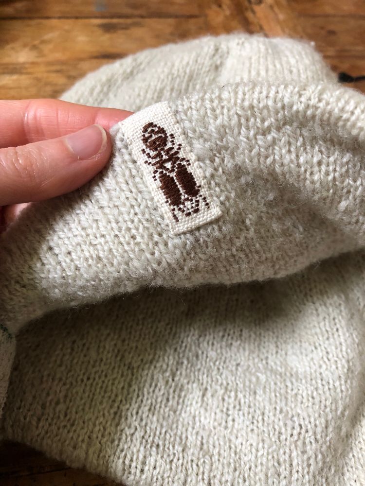 Close up of a woven garment tag with the image of a big-headed ant woven into it. 