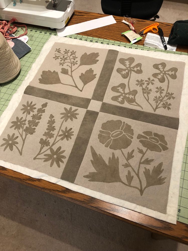 The start of a wall hanging featuring olive green/grey floral designs on beige linen. The designs were dyed using an iron mordant paste and used espresso grounds