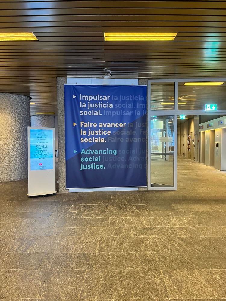 A large poster with writing of a phrase in Spanish, French and English with a concrete floor.
