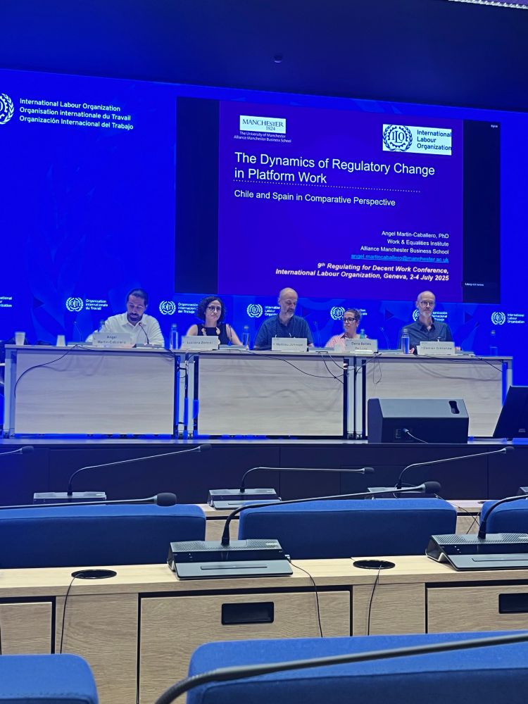 A panel of 5 people presenting at a conference