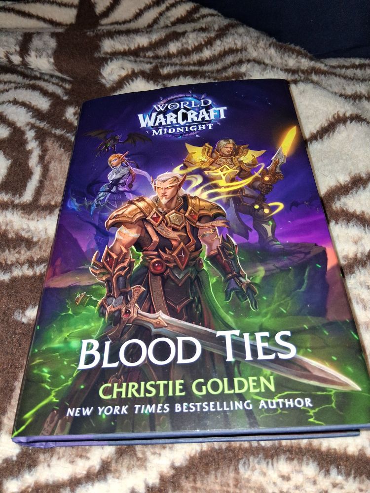 Looks at this beautiful $/42cdn hard cover book i found at the coles aka indigo/chapters Canadian book store, it was the last in stock but boy it is a expensive pretty book. Title is: World of Warcraft's Midnight: Blood Ties, by Christie Golden. Shows 3 lore characters from wow, which are: top left is a female elf in white n blue armor, on the right is a human male in goldenish holy armor and the bottom middle is their son a half elf/human in red n gold armor.