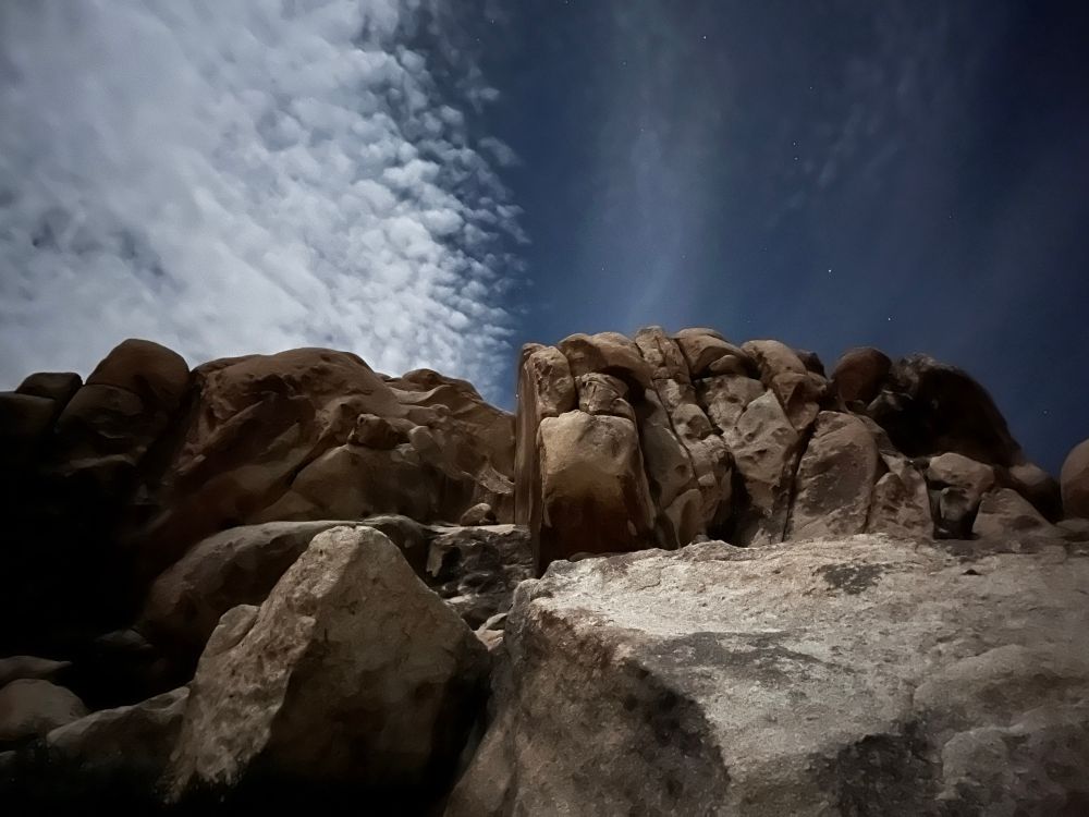 Moonlit boulders under a partly cloudy sky