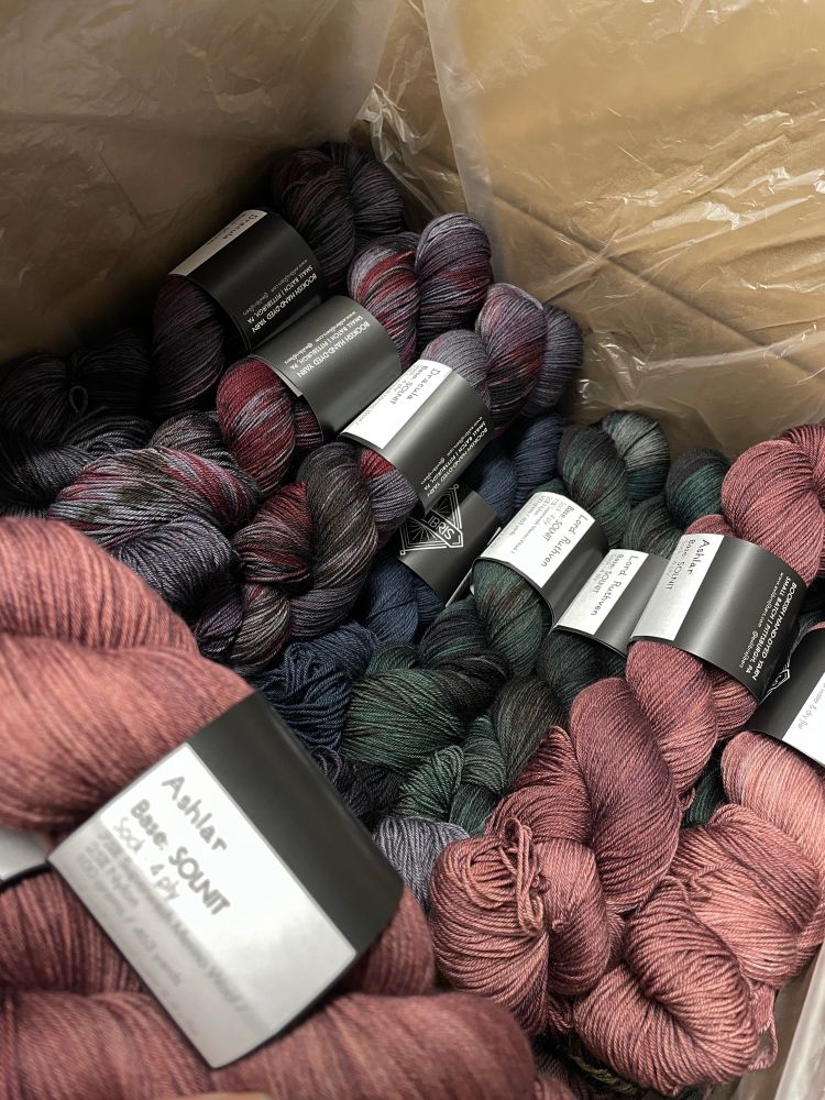 Many finished bookish hand dyed yarns in a shipping box 