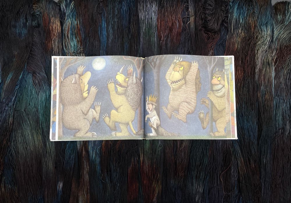 Maurice Sendak Where the Wild Things Are rumpus pages open on top of matching indie dyed yarn