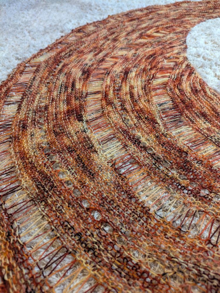 A close up view of a finished Storm Shawl, a lacy knit shawl pattern by Joji Locatelli, knit up in Ex Libris Fibers limited banned book fundraiser color inspired by The Catcher in the Rye