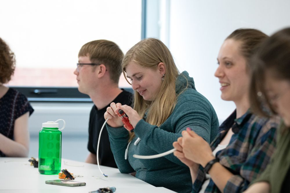 Three Grantham Scholars sitting a table, using pliers to try and rewire a plug.
