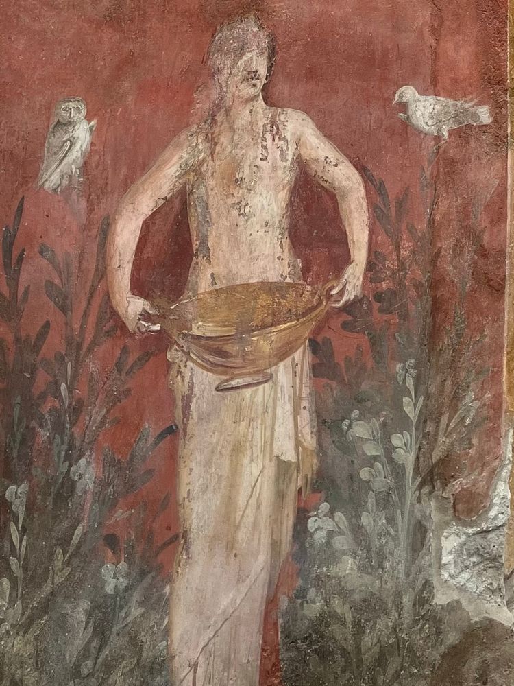 Nymph holding a golden bowl, an owl to her left and a dove to her right, against a red background.