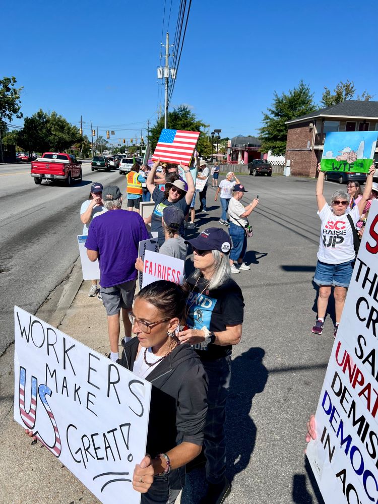 Protesters on the sidewalk next to Remount Rd in Hanahan, SC. The sign upfront says 