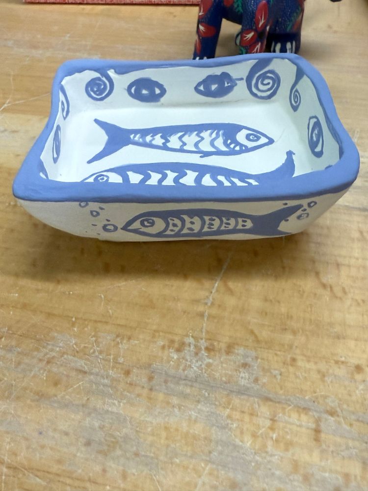 Small, white, ceramic dish with a farting sardine in blue.