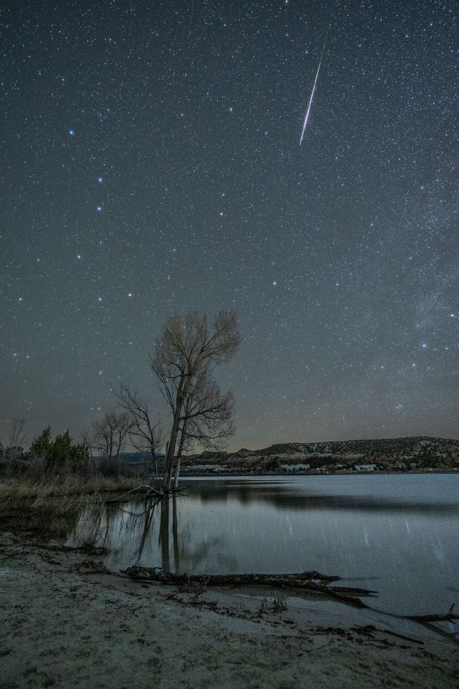 A meteor falling over a placid lake 