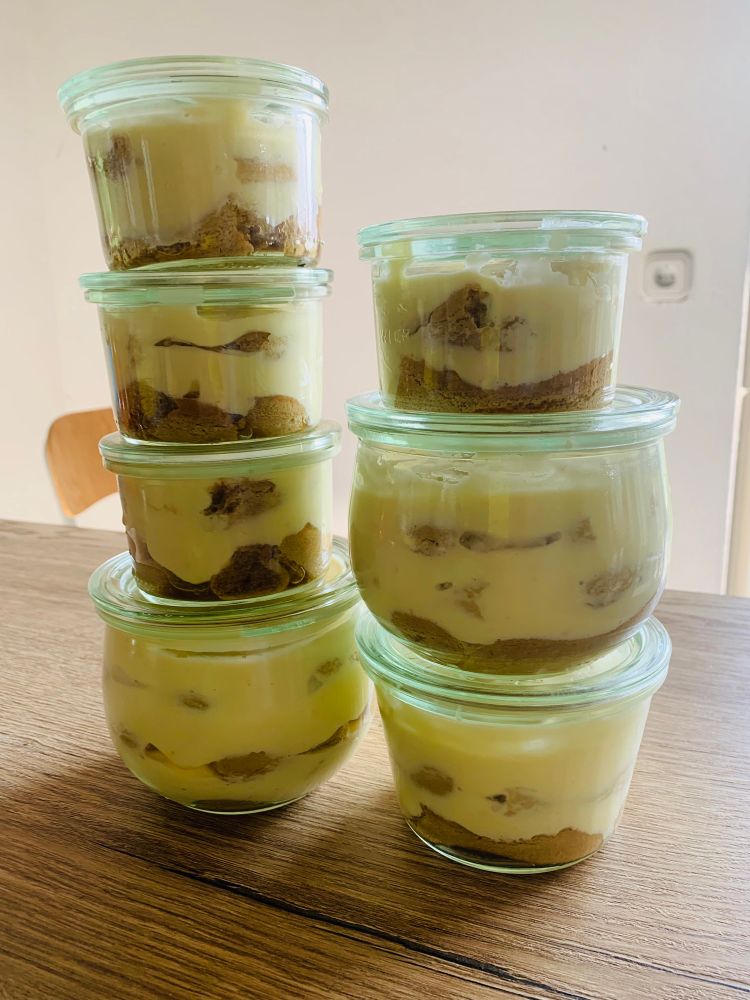 Verschieden große Gläser mit Tiramisu stehen in zwei Stapeln aufeinander. 