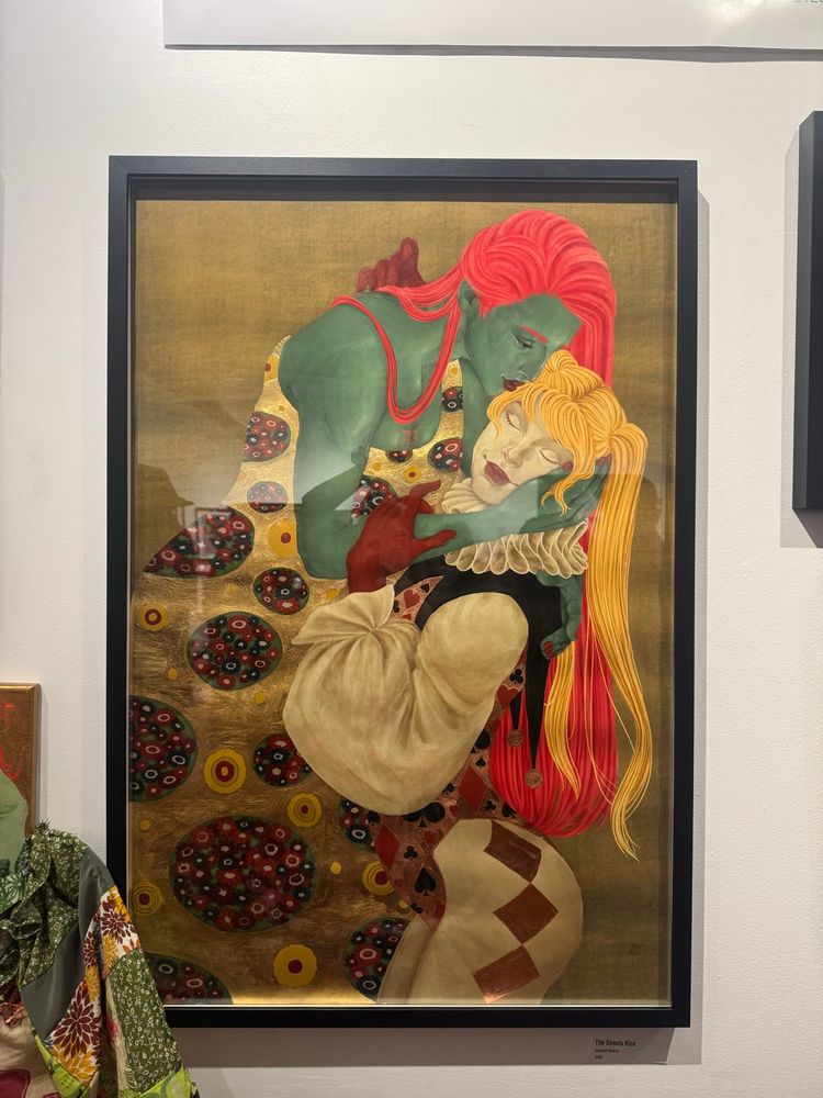 A photo of an illustration, heavily inspired by Klimt’s “The Kiss,” of Poison Ivy, draped in a floral-patterned dress, kissing the temple of Harley Quinn, who is wearing a ruffled collar and a leotard that is patterned in card suits.