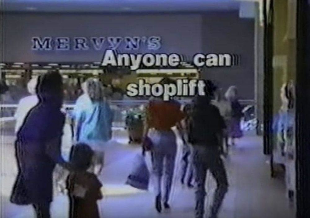 Screencap of a PSA from the 90s. There are shoppers in what appears to be a mall. A store named Mervyn's (unsexy name for a store but whatever) is in the background. Text in the screen says "Anyone can shoplift" in block letters.