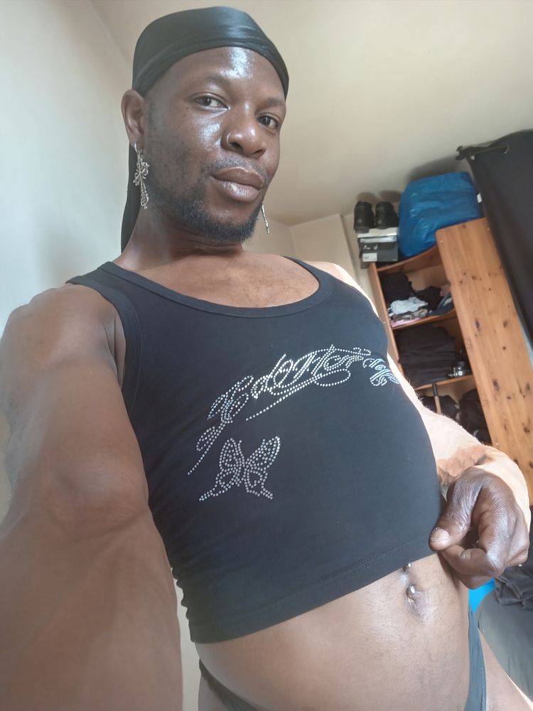a selfie of me in my room, i'm wearing an Ed Hardy crop top with a rhinestone butterfly pattern, a black durag and a thong.
