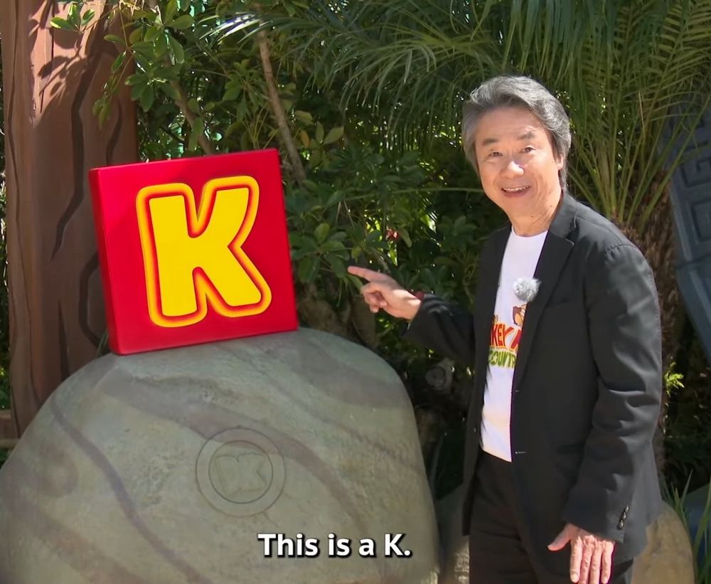 Shigeru Miyamoto is standing next to the Letter K: “This is a K.”