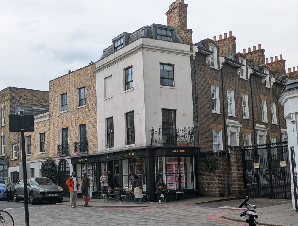 Photograph of the outside of a bookshop with customers sat at tables on the pavement outside