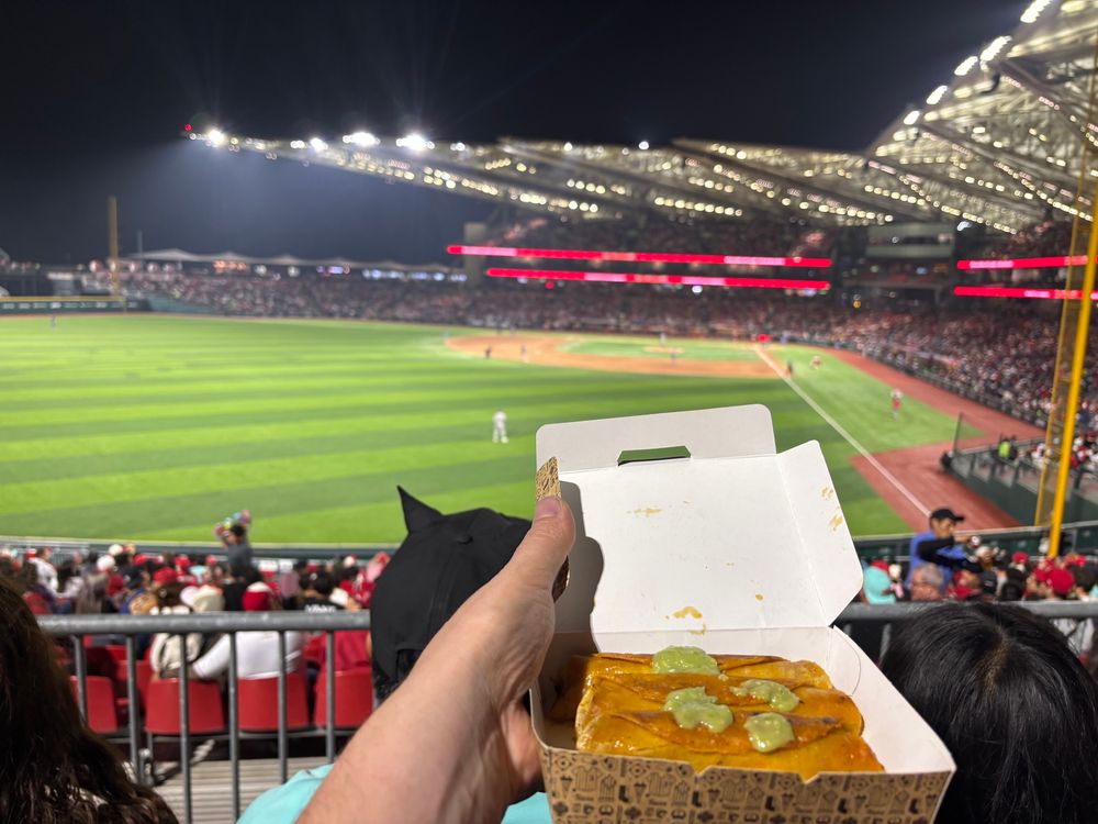 Three tacos at a baseball game, 
 Americans might recognize them as taquitos  