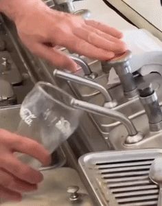 a person is pouring water into a glass with the word coca cola on it