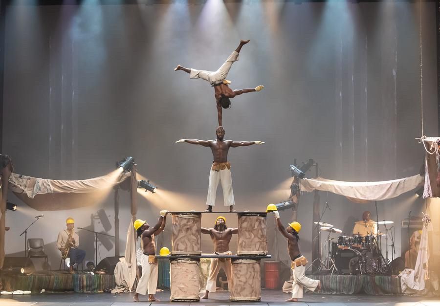 Publicity shot of acrobats balancing in a pyramid on stage