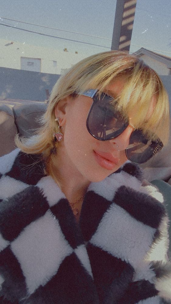 AnarchoCummunist taking a selfie in a black and white checkered jacket and black sunglasses. 