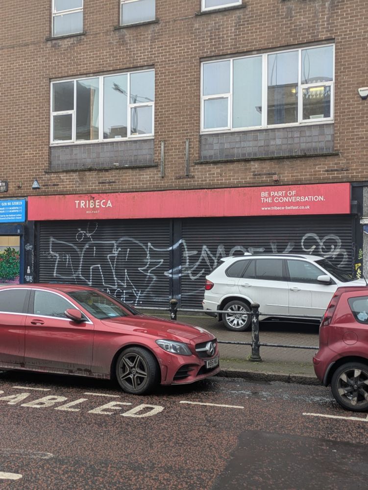 An empty shop front in Lower North Street in Belfast with signage for the Tribeca scheme.