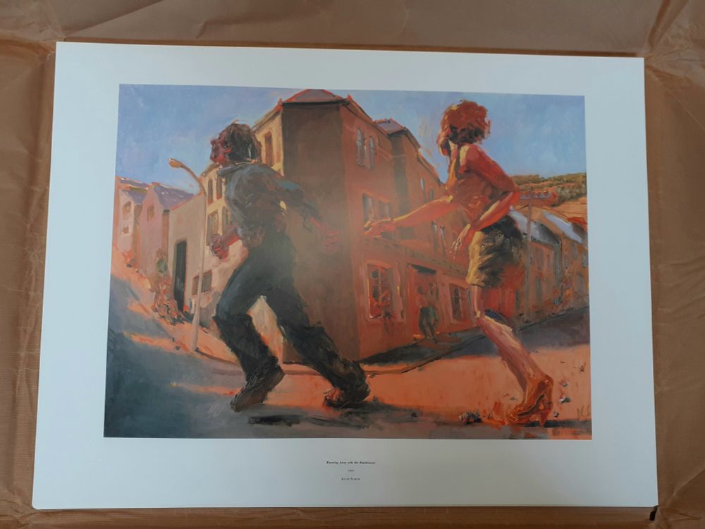 Poster laying flat on floor. It depicts a painting of two figures running past the corner of a terraced street