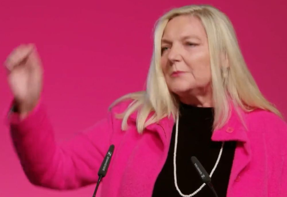 Blonde Frau in pinker Jacke vor pinkem Hintergrund