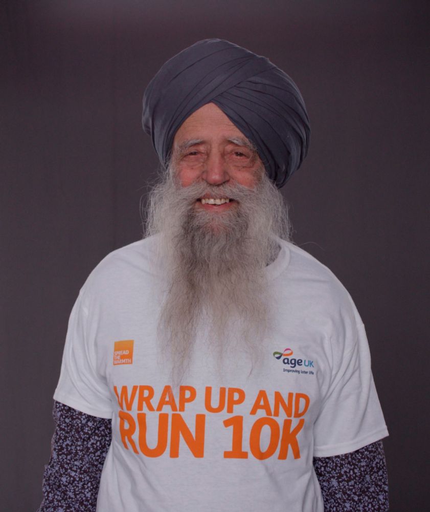 Fauja Singh smiles at the camera in an Age UK t-shirt