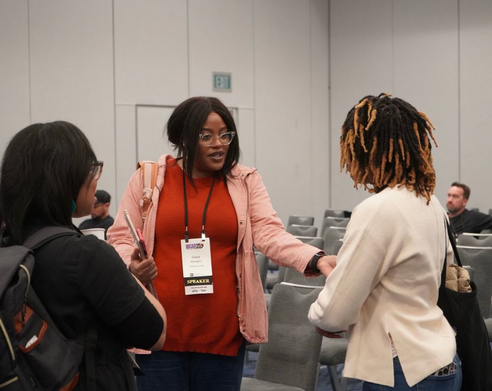 Three conference attendees speaking with each other in panel room