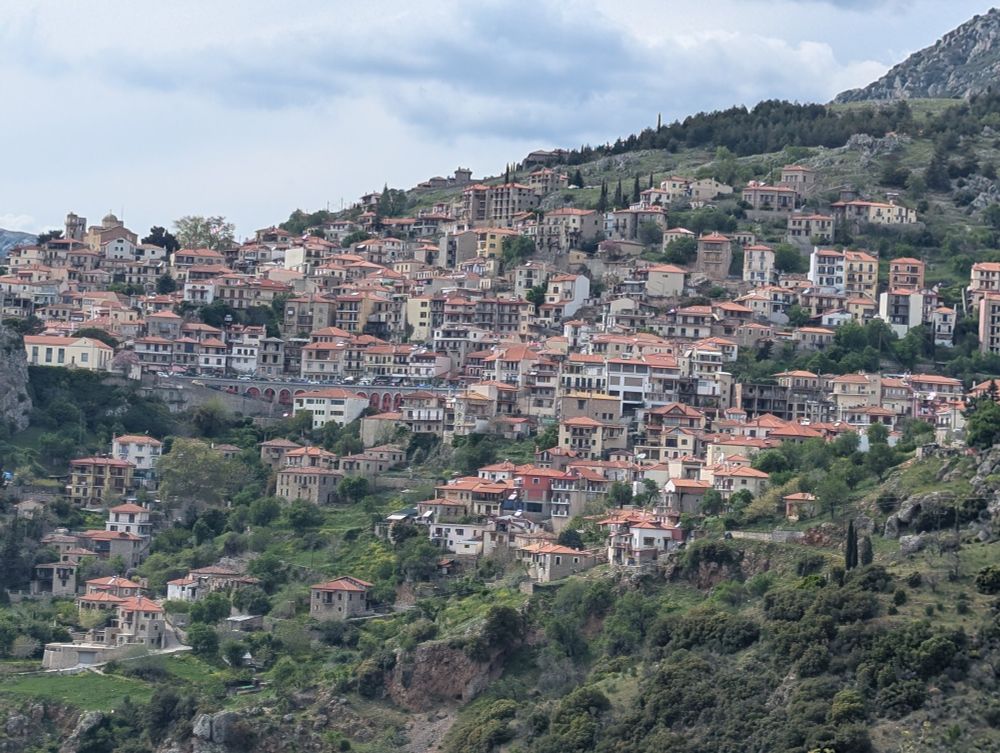 A view of Arachova, a Greek city on the side of a mountain with white buildings and red roofs