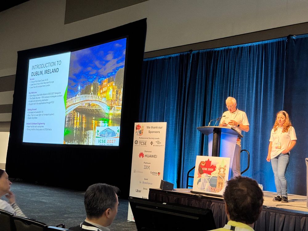 Two people on a stage and a projected slide showing Dublin. 