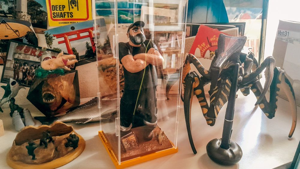 Voila la figurine sous sa coque en plastique, posée sur mon bureau entre une tête de piranha, un gros Arachnid en plastique et quelques cartes postales, souvenirs de mes voyages en Australie. Je suis donc là, les bras croisé, me jugeant d'un oeil noir. Au moment où je tape ses lignes il est là, sur mon bureau, à me juger. Une sorte de mise en abyme ébouriffante.