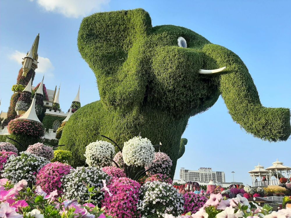 Olifant van klimop met op de achtergrond een boeken kasteel en voor de olifant veel roze en witte petunia's 