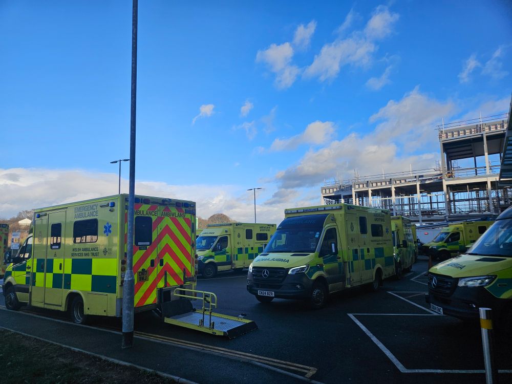 Multiple Emergency Ambulances parked outside an Emergency Department waiting to transfer care of patients to hospital.