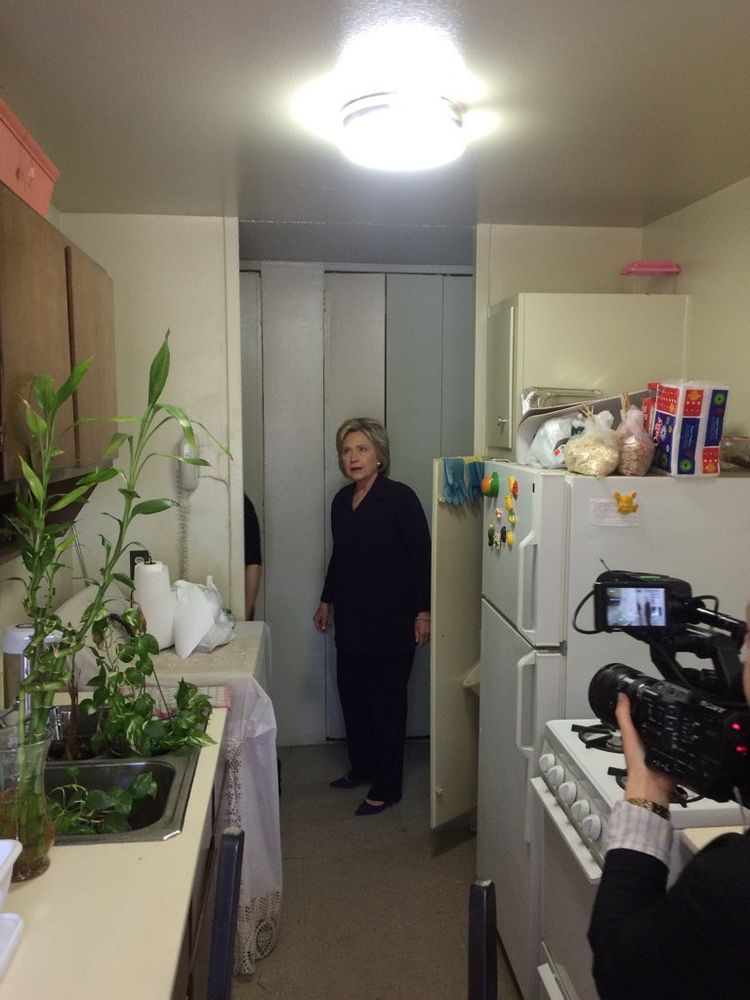 Hillary Clinton looking at a plant in an apartment sink 