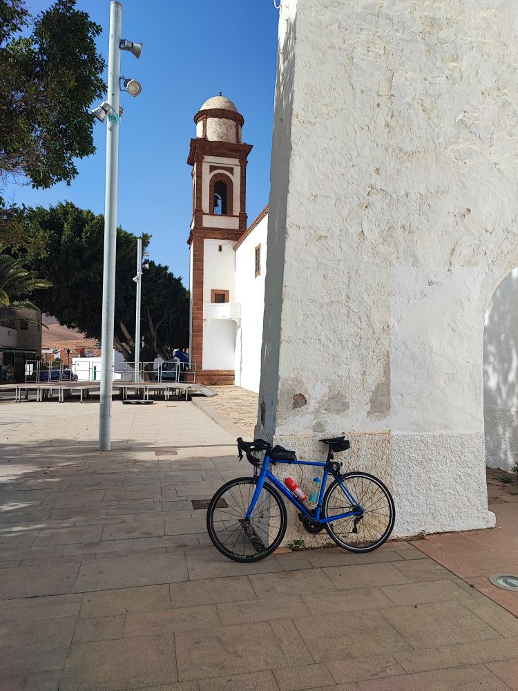 Blaues Mietrennrad steht gegen eine Wand. Im Hintergrund ist ein Kirchturm.