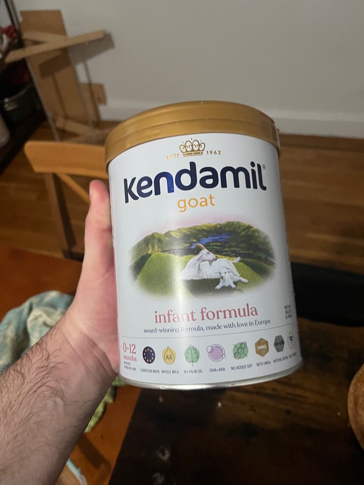A hand holds a container of Kendamil Goat milk infant formula
