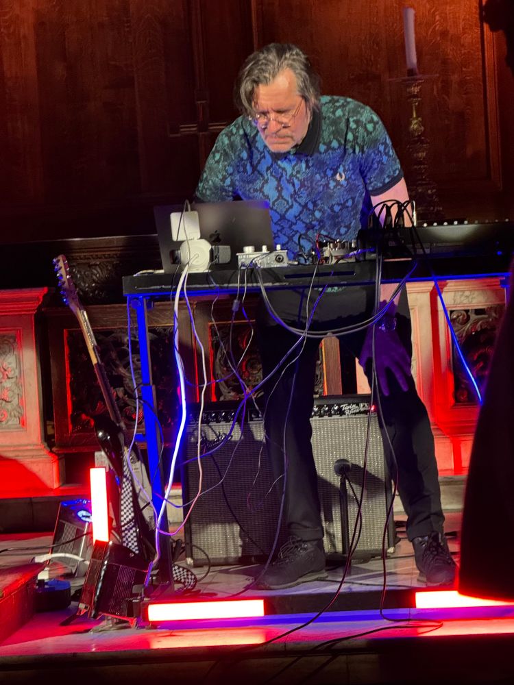 Christian Fennesz frowning in concentration as he stoops over a laptop