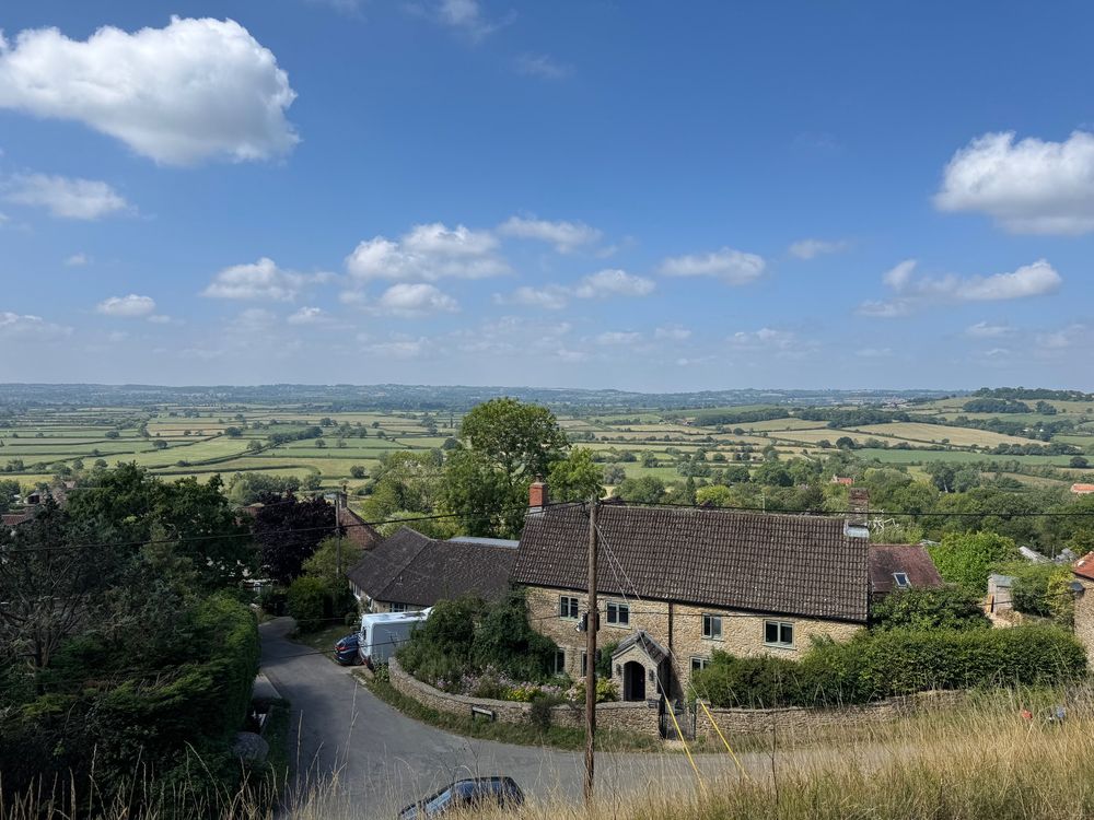 View from a high vantage point over a sunlit valley with hills in the distance. I rode up there (well, mostly)