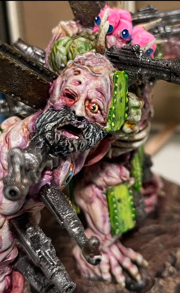 Close up of a war gaming miniature, a freaky amalgam, and the bearded face on its shoulder. 