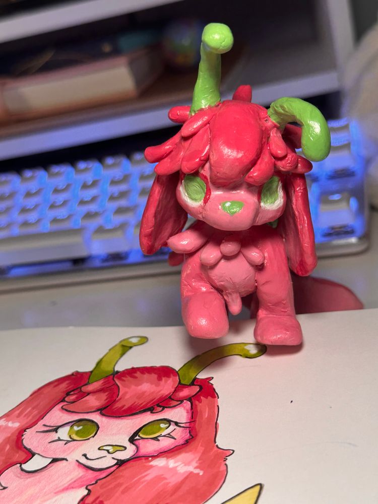 A close up of the polymer clay sculpture of Lychee. One front paw is lifted whilst the other is on the edge of the sketchbook pages.