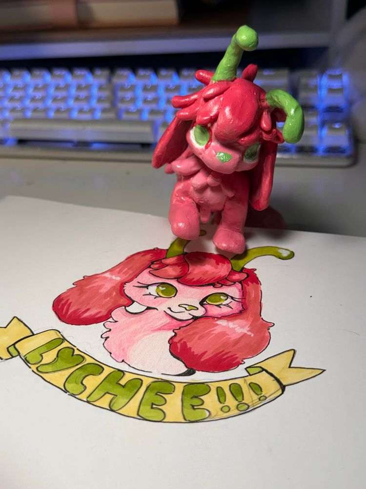 My character Lychee- a snail/ cocker spaniel. A polymer clay sculpture of her is standing partially on top of her character badge done with alcohol markers and coloured pencil.