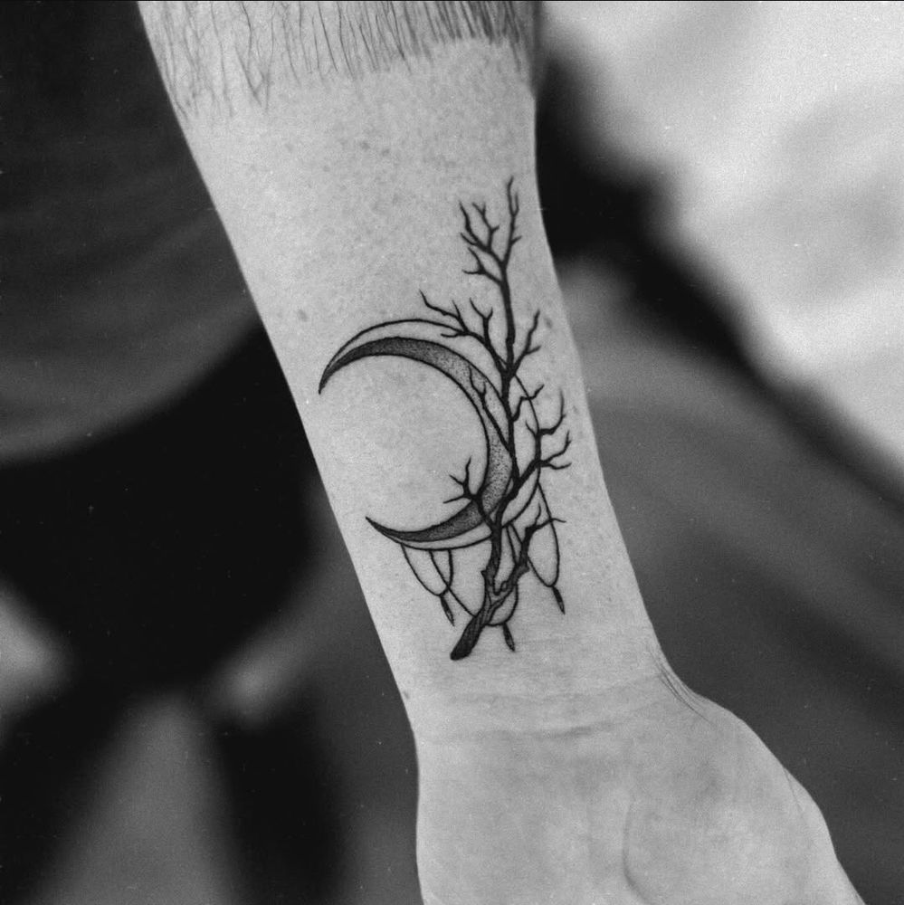 a crescent moon tattoo, with a thorny branch and some small accents