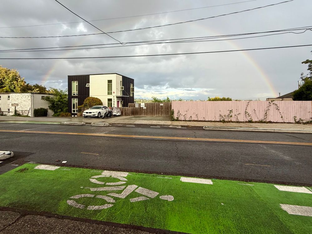 Wide angle view of a rainbow in the sky over a new protected bike lane on Beacon Hill 