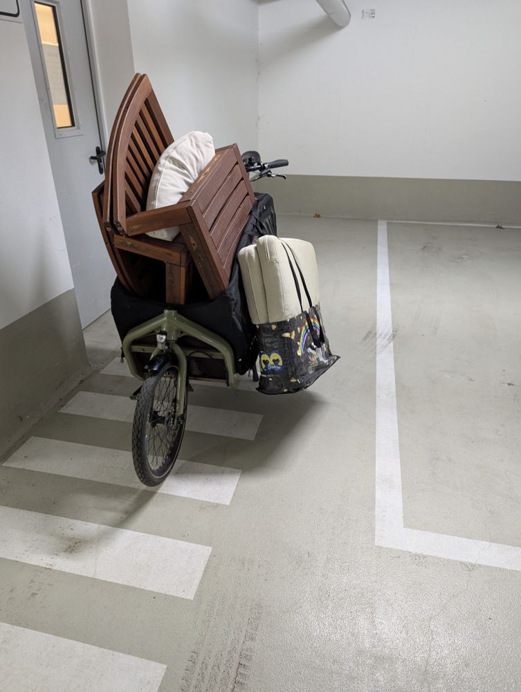A flat packed Ikea outdoor sofa including cushions packed into a front loading cargo bike
