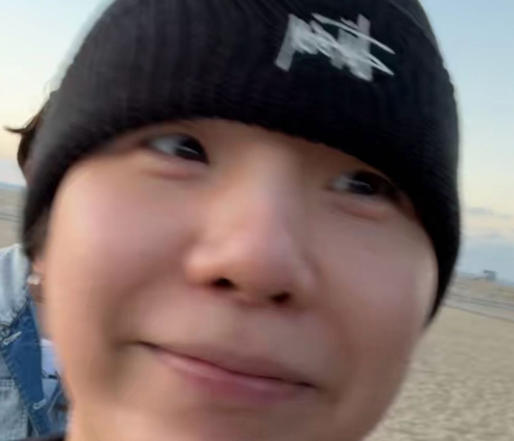 of course I had to use this one. blurry close-up photo of yoongi from the aug 16 beach weverse live. he’s wearing a black beanie low over his eyebrows and making a silly frog face 