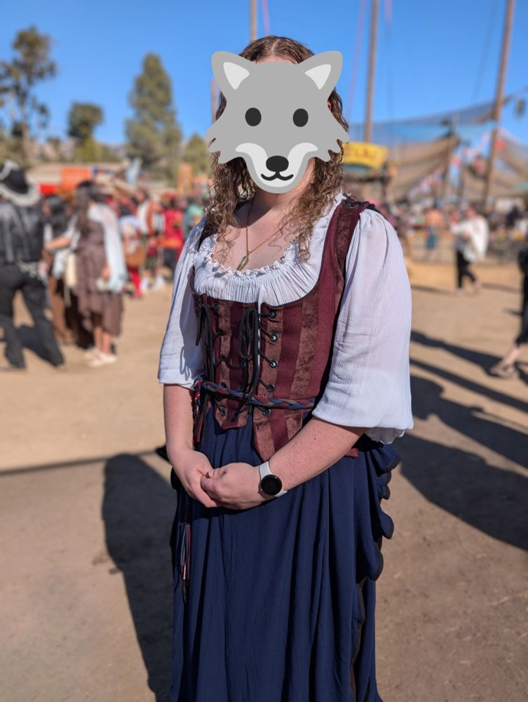 Picture of myself at the Renaissance Faire wearing a traditional outfit consisting of a white blouse, red striped bodice, and blue skirt over a brown skirt. 