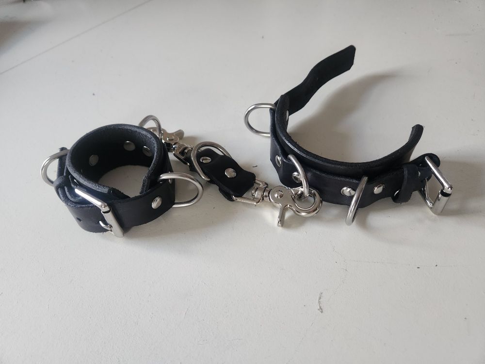 black heavy duty bondage cuffs. each cuff has 3 D rings. connecter has 1 D ring in addition to clips